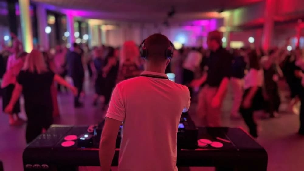 DJ Canis am Mischpult vor einer Tanzfläche mit feiernden Gästen